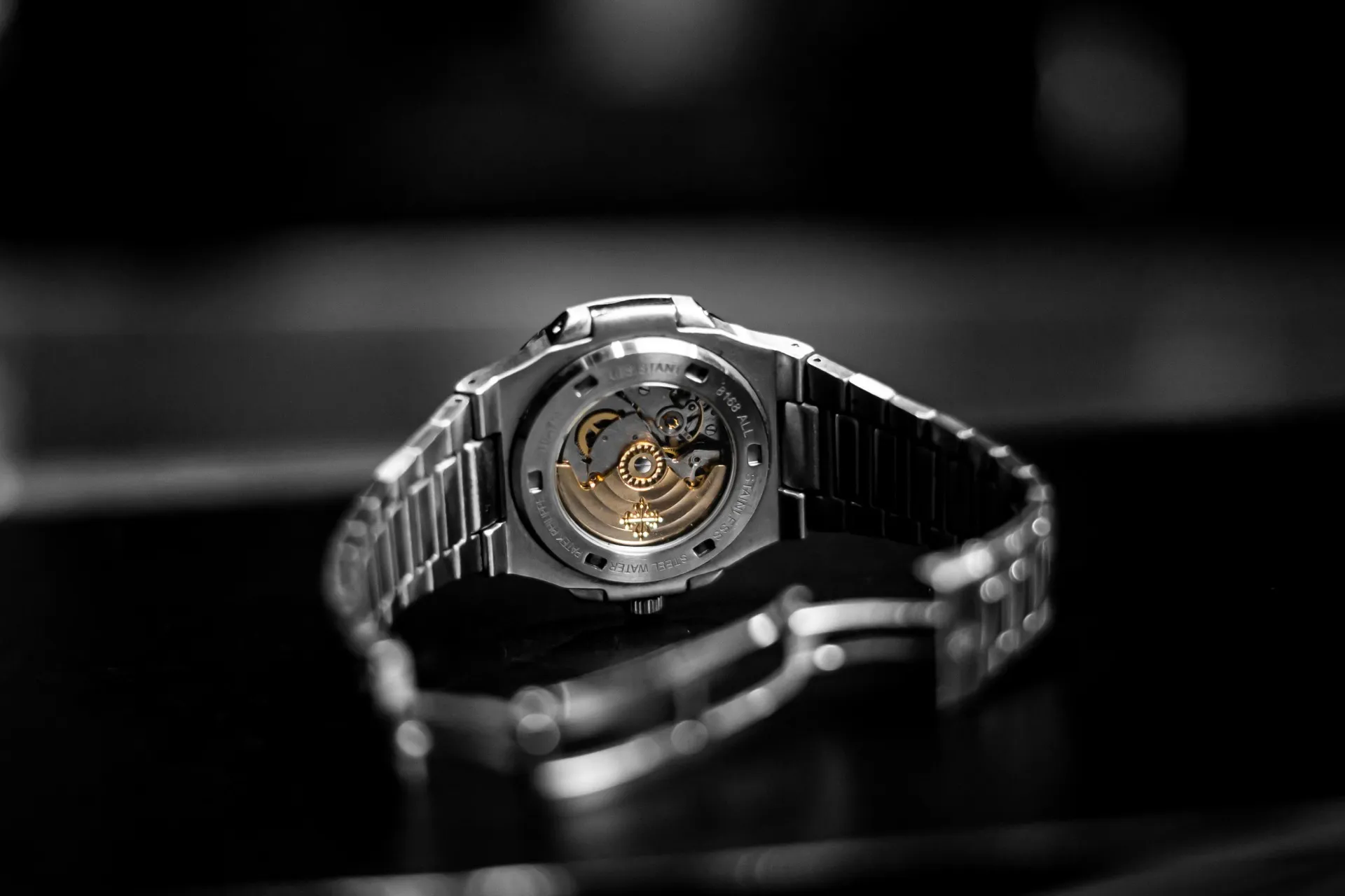 Transparent caseback of a luxury sports watch showing the automatic movement with gold rotor