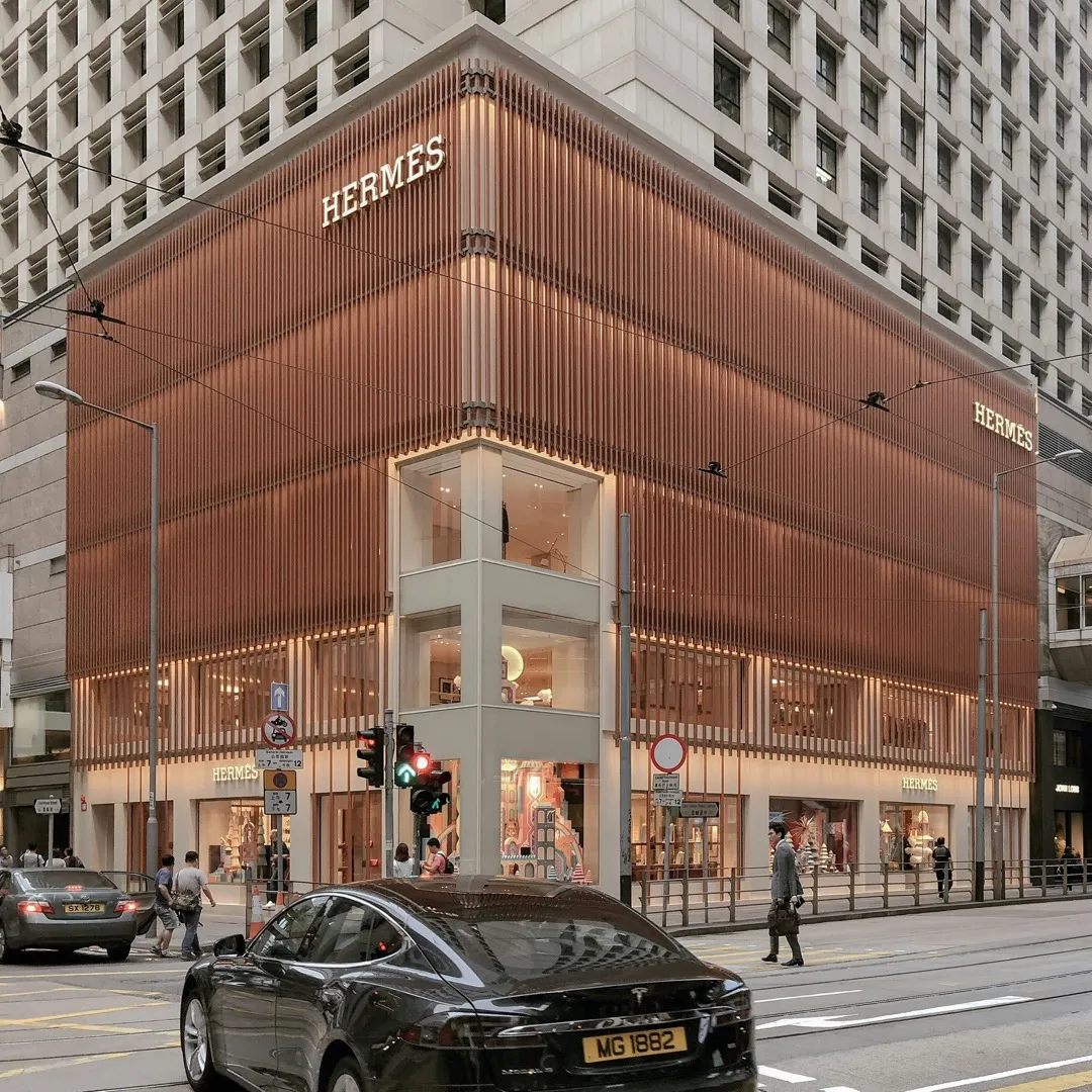 Modern Hermès flagship store with copper facade and corner window displays in a major city