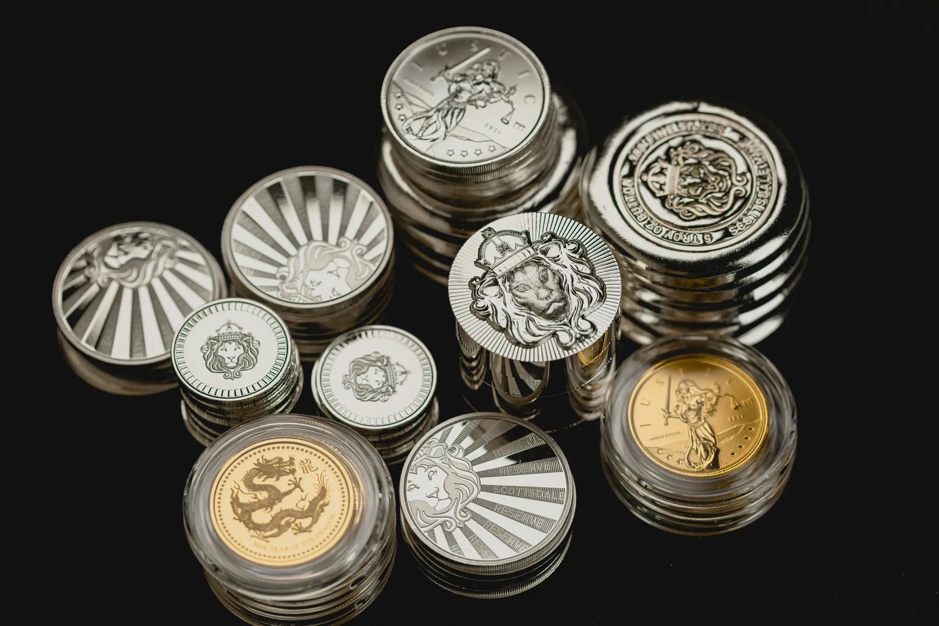 Collection of silver and gold bullion coins in protective capsules on black background
