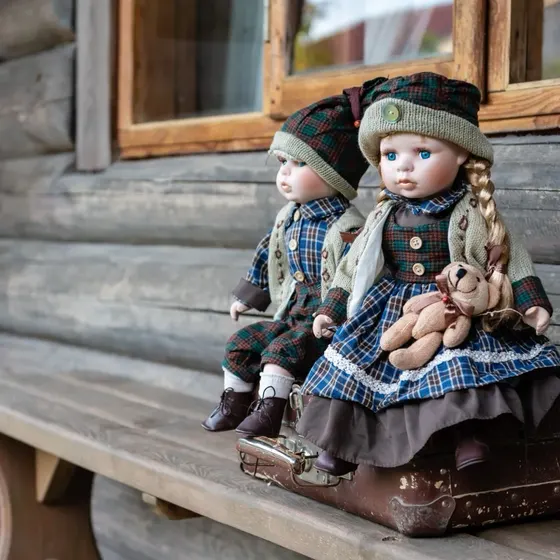 Two antique dolls sitting on a suitcase