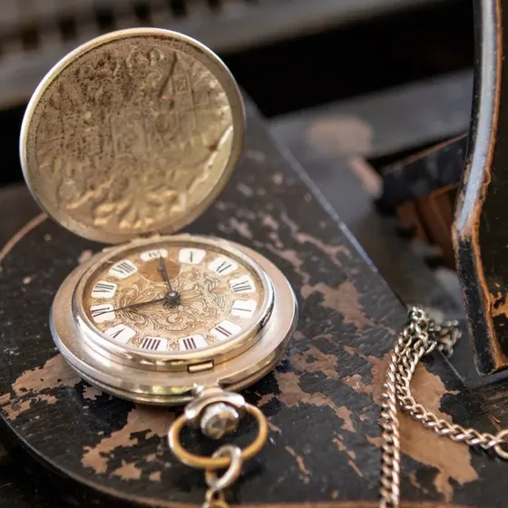 An open-face antique pocket watch on its chain