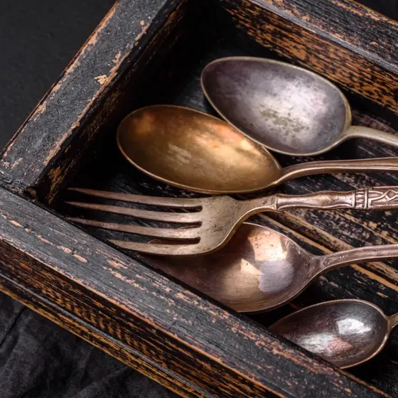 Old silver spoons and a fork in a wooden box