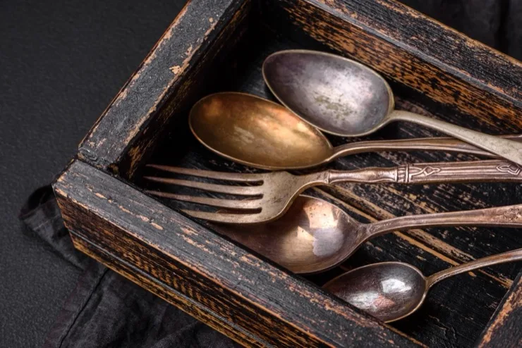 Vintage tarnished silverware — spoons and fork — in a distressed wooden box