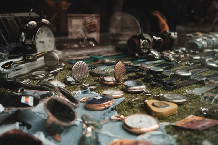 Collection of vintage pocket watches and wristwatches displayed on a cloth at a flea market
